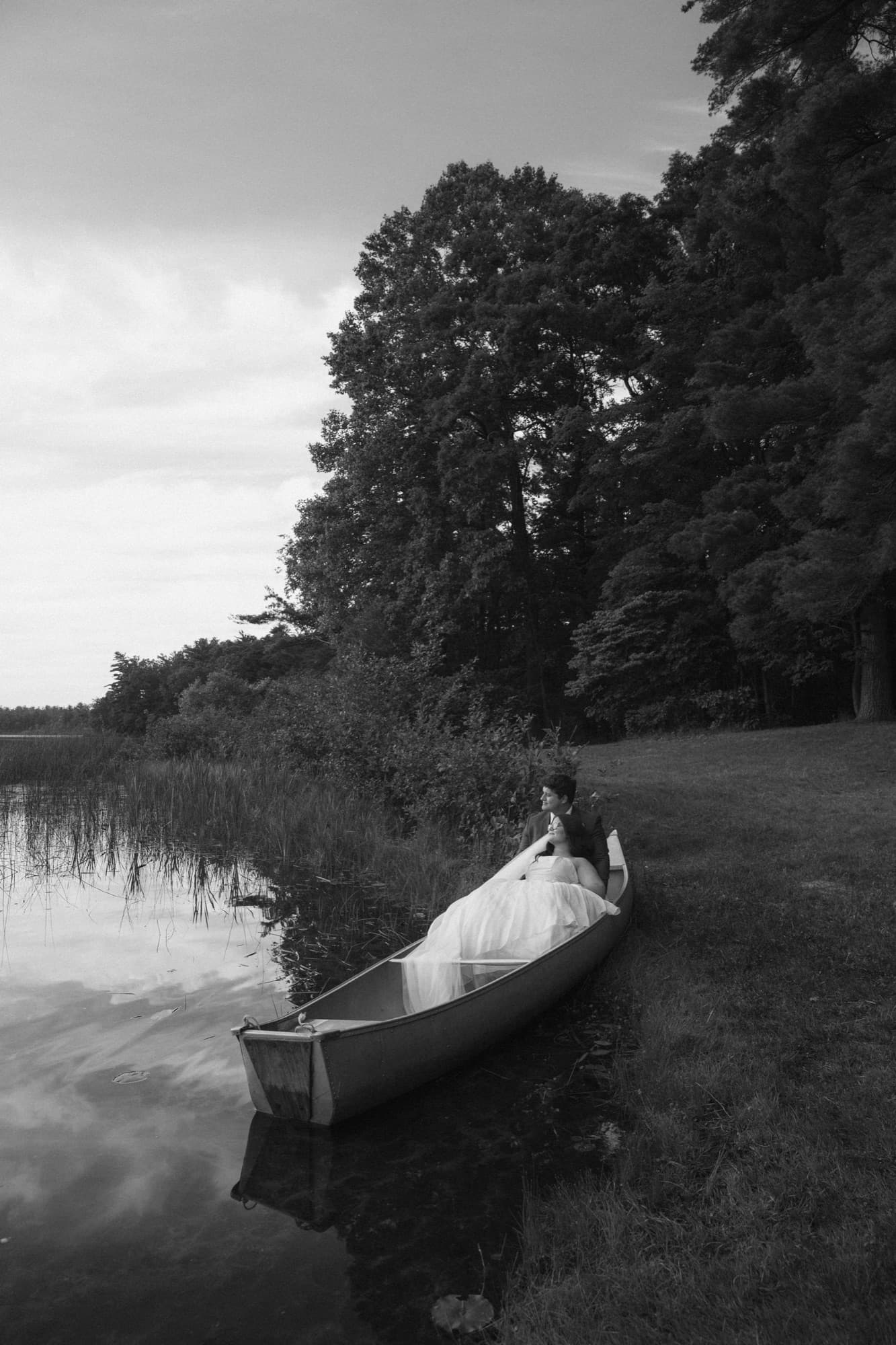 A bride sitting in a canoe at the edge of Long Lake