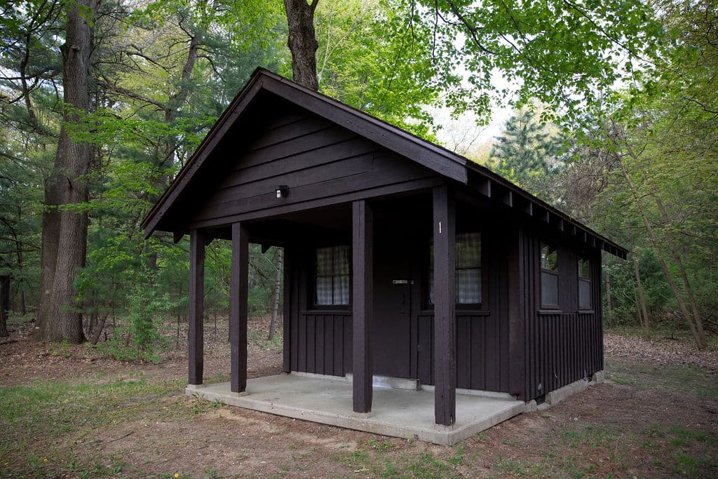 CCC-built cabin with a covered porch under the trees at Long Lake