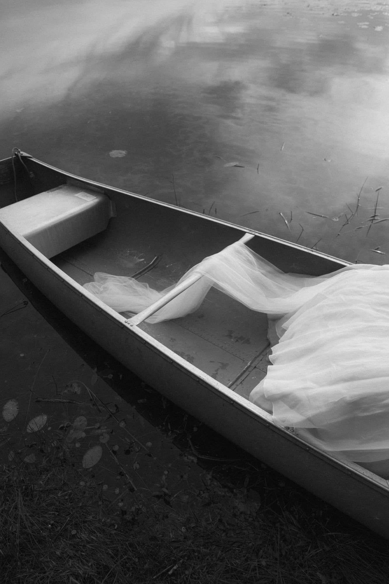 A wedding veil draped across a canoe on the water