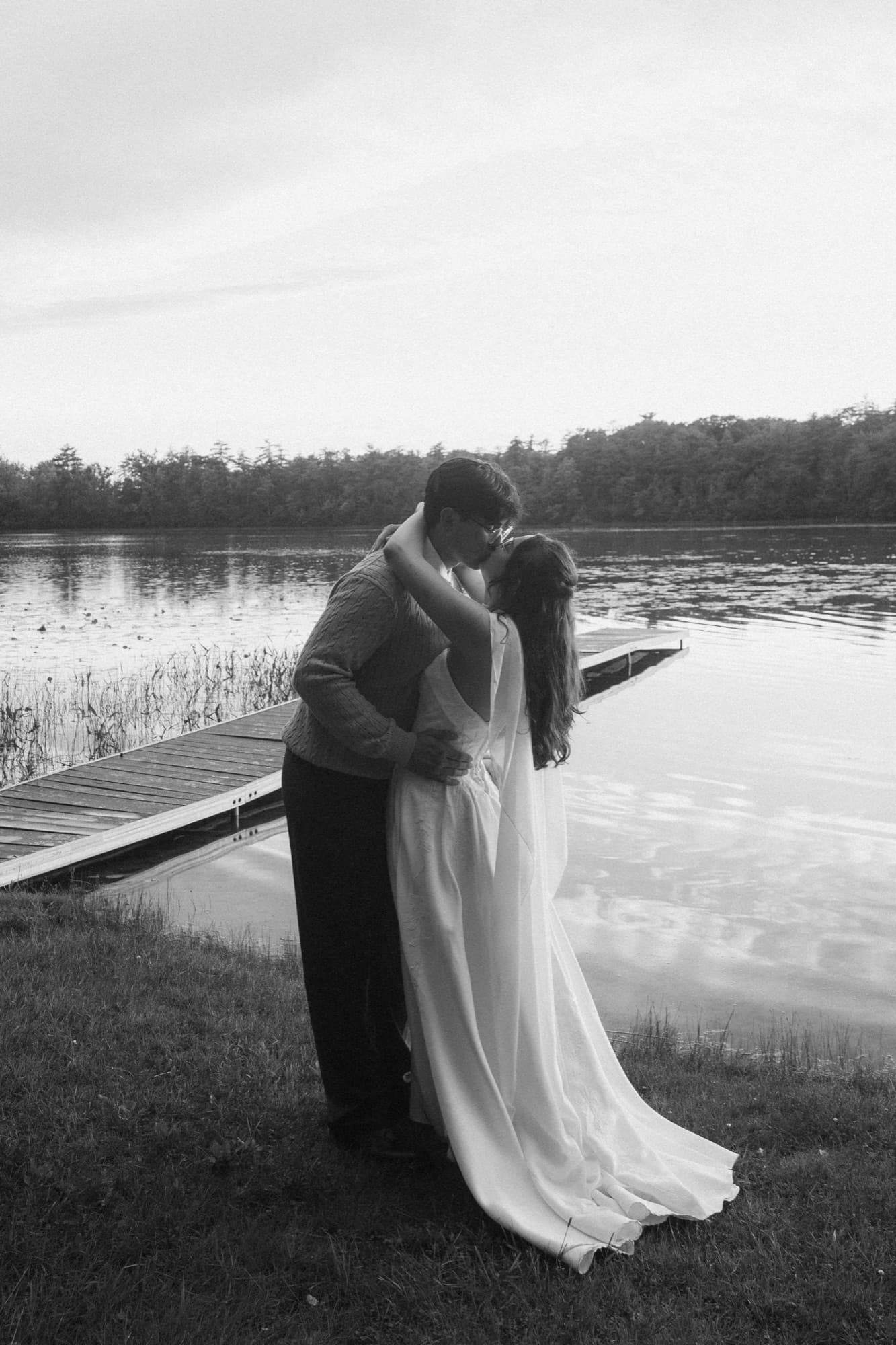 A bride and groom kissing beside the dock on Long Lake
