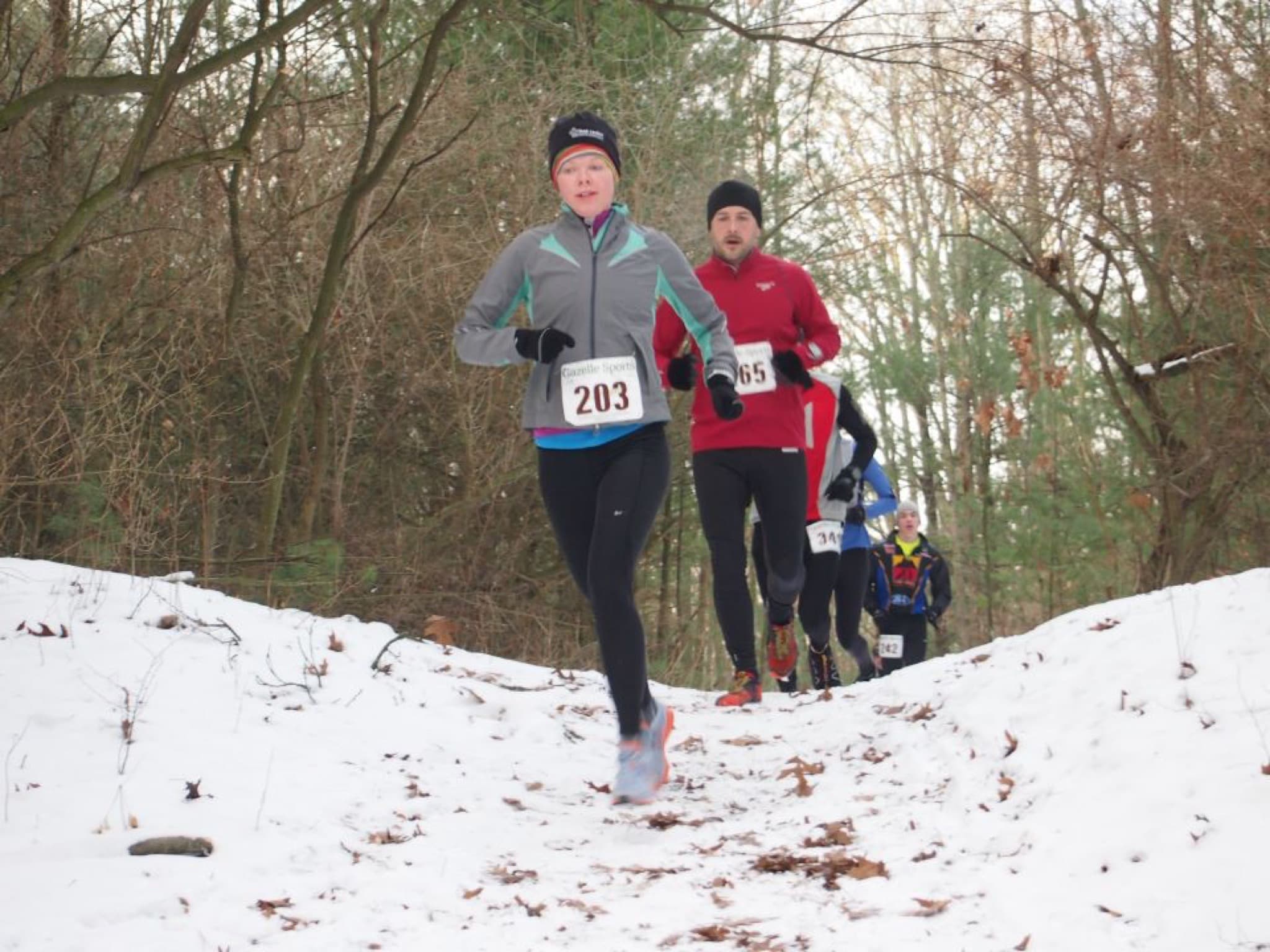 Runners racing on a snowy wooded trail